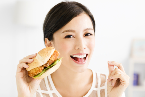 female-eating-burger-after-taking-invisalign-out